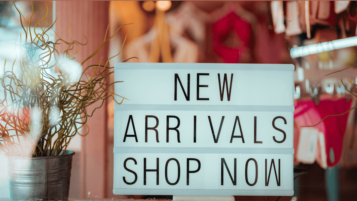Lightbox sign reading “New Arrivals Shop Now” displayed in a boutique window – newest arrivals collection banner for Zazations
