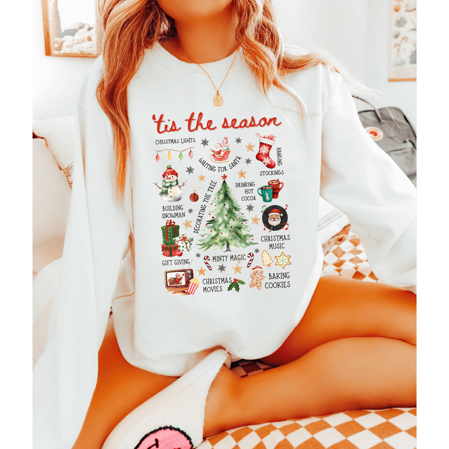 Person wearing a white sweatshirt with Christmas-themed graphics and text.