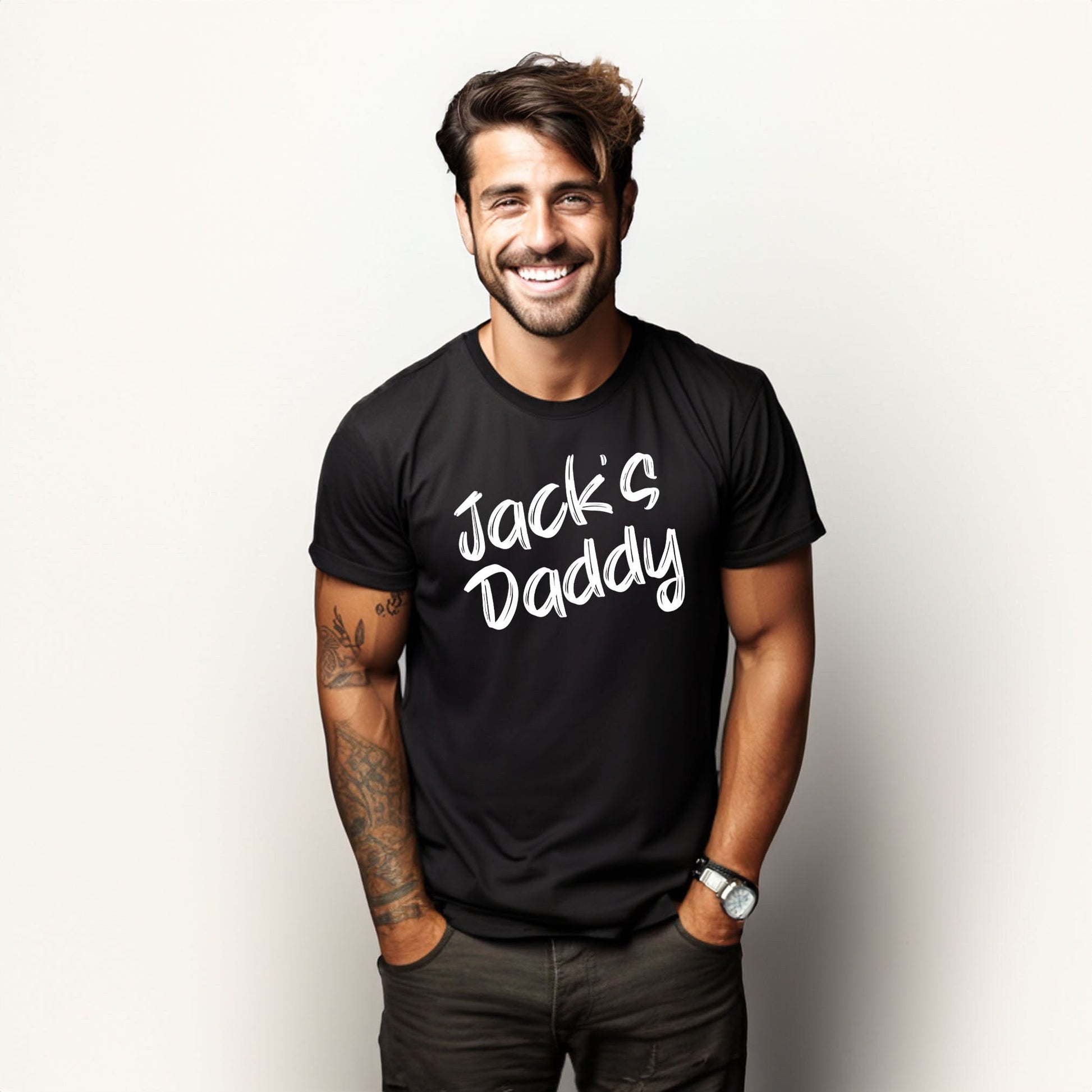 Smiling man wearing a black t-shirt that says "Custom Name's Daddy" in playful white font.

